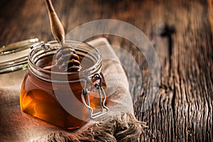 Honey jar with dipper on old woodn table