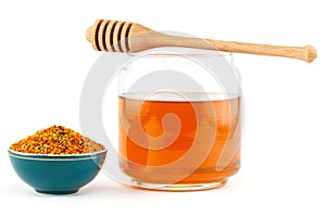 Honey in jar with dipper and pollen on isolated background