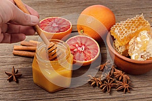 Honey in jar and honey combs in bowl with oranges and Badian on table, healthy natural food concept