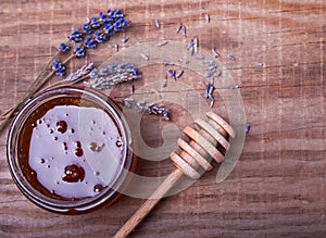 Honey in a jar, honey spoon and lavender flowers on the wooden t