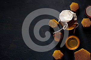 Honey in a jar and a honeycomb. On a black wooden background. Free space for text. Top view