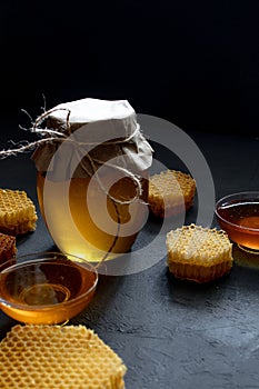 Honey in a jar and a honeycomb. On a black wooden background. Free space for text. Top view