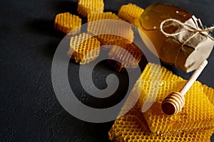 Honey in a jar and a honeycomb. On a black wooden background. Free space for text. Top view