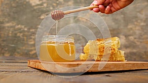 Honey in a jar and honeycomb on old wooden background.