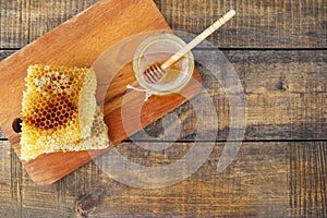 Honey in a jar and honeycomb on an old wooden background.