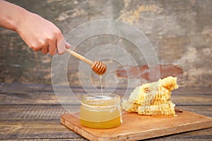 Honey in a jar and honeycomb on old wooden background