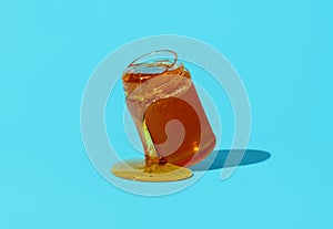 Honey jar isolated on a blue background. Pouring honey from jar