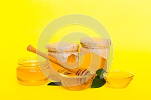 Honey in jar with leaves and honey dipper on colored background top view with copy text