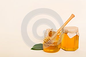 Honey in jar with leaves and honey dipper on colored background top view with copy text