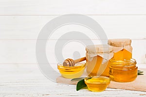 Honey in jar with leaves and honey dipper on colored background top view with copy text