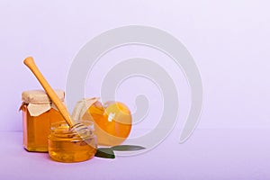 Honey in jar with leaves and honey dipper on colored background top view with copy text