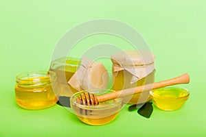 Honey in jar with leaves and honey dipper on colored background top view with copy text