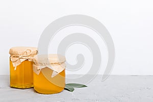 Honey in jar with leaves and honey dipper on colored background top view with copy text