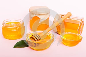 Honey in jar with leaves and honey dipper on colored background top view with copy text