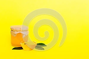 Honey in jar with leaves and honey dipper on colored background top view with copy text