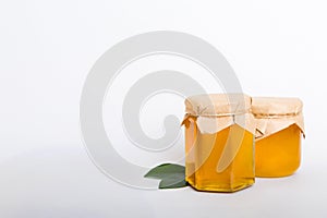 Honey in jar with leaves and honey dipper on colored background top view with copy text