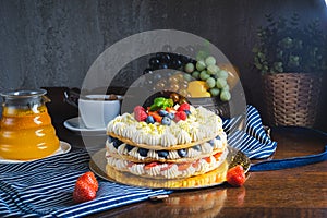 Honey layer cake with whipped cream, strawberries and blueberries on the table.