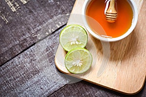 Honey lemon lime on cutting board with honey cup on dark wooden background