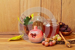 Honey, pomegranate, grapes and autumn leaves over natural wooden background