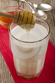 Honey is poured into a glass of warm milk