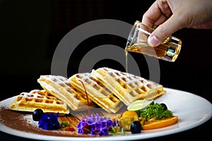 Honey pouring on a fresh waffles on a plate. Breakfast with waffles in morning