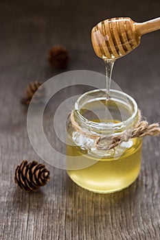 Honey pours with wooden sticks in a jar