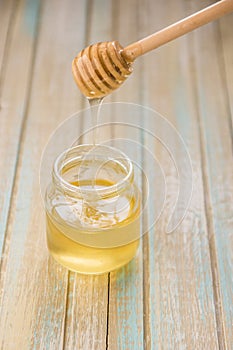 Honey pours with wooden sticks in a jar