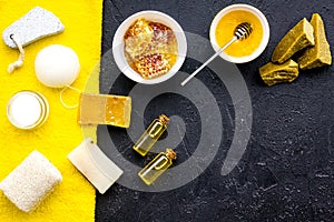 Honey spa set with natural honey, soap, cream, towel and pumice stone on black background top view space for text
