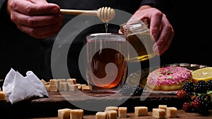 Honey on a spoon, black tea and donuts. Food close-up photography 4k