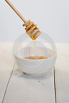 With a honey spoon a bowl is filled with flower honey