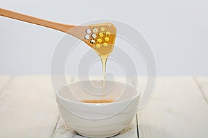 With a honey spoon a bowl is filled with flower honey