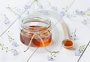 Honey in a spoon and jar decorated forget-me-not flowers