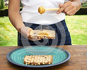 Honey with stick pouring over toast