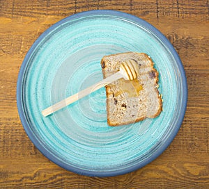 Honey with stick pouring over toast bread