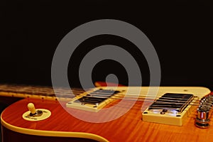 Honey sunburst vintage electric blues guitar closeup on the black background, with plenty of copy space.