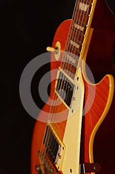 Honey sunburst vintage electric blues guitar closeup on black background. Shallow depth of field.