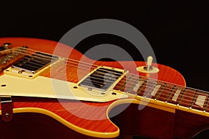 Honey sunburst vintage electric jazz guitar closeup on black background. Shallow depth of field.