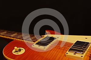 Honey sunburst vintage electric rock guitar closeup on black background, with plenty of copy space. Selective focus.