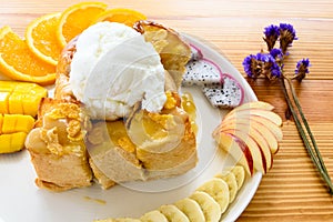 Honey toast with coconut ice cream and fruits on a wooden table.