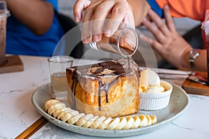 Honey toast served with banana slices, vanilla and chocolate ice cream on light green ceramic plate