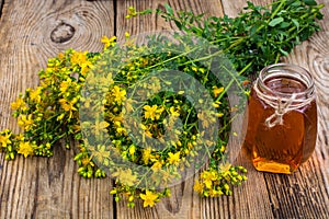 Honey in transparent glass jar and fresh St. John`s wort flowers on rustic background