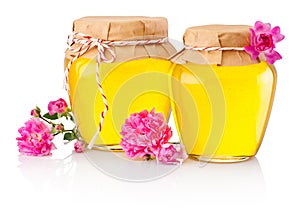 Honey in two glass jars and flowers isolated on white background