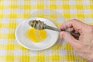Honey wand in man's hand over saucer