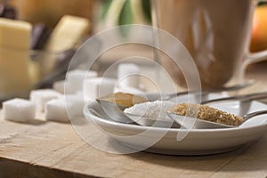 Honey, white sugar, cane sugar in the foreground enlarged. In the background, sugar cubes lie on a wooden board.