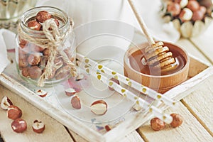 Honey in the wooden bowl, hazelnuts and jar with milk on the wooden tray