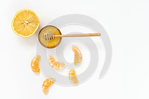 honey in a wooden bowl and orange on a white background.