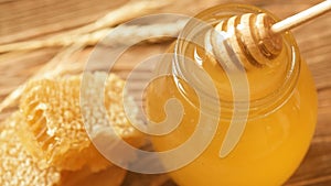 Honey with wooden honey dipper and glass jar