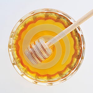 Honey with wooden honey dipper in the glass jar top view