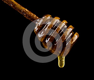 Honey on wooden spoon isolated on black background