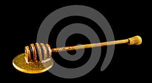 Honey on wooden spoon isolated on black background